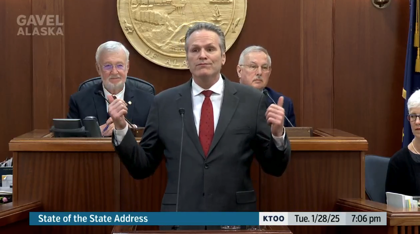 Gov. Mike Dunleavy stands at a podium at the center of the Alaska State House for his annual State of the State address. Behind him, Senate President Gary Stevens and House Speaker Bryce Edgmon sit. Dunleavy looks like he's gesturing at them with his thumbs in a sort of Fonz kind of motion, but he's gesturing at the vote boards in a Fonz kind of motion.